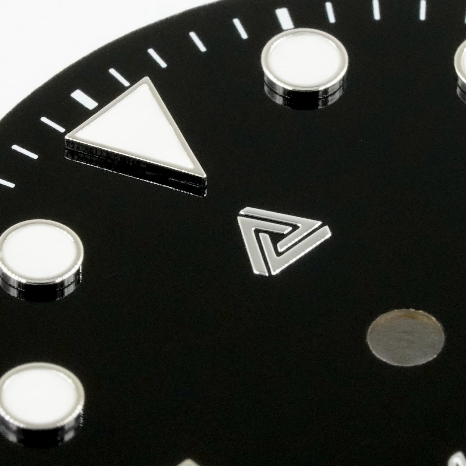 Macro of the glossy black enamel Submariner II dial — raised bevelled silver hour markers with cream lume fill and the applied polished-silver Lucius Atelier logo