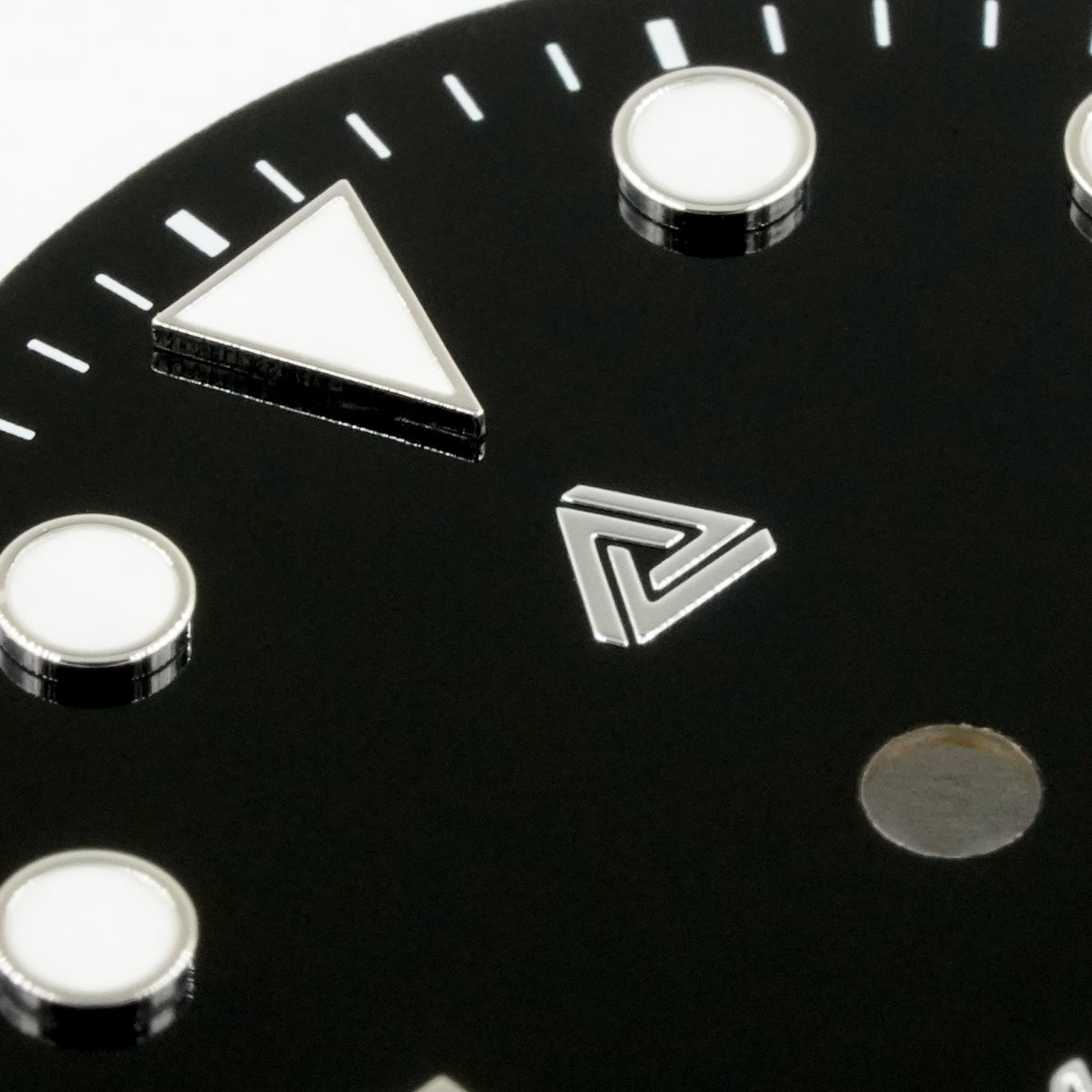 Macro of the glossy black enamel Submariner II dial — raised bevelled silver hour markers with cream lume fill and the applied polished-silver Lucius Atelier logo